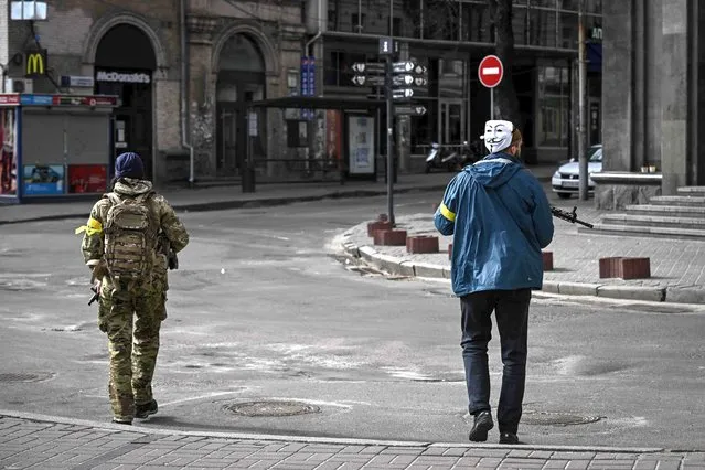 A member of Ukrainian forces, wearing Guy Fawkes mask (Anonymous mask), patrols downtown Kyiv, on February 27, 2022. Kyiv authorities on February 26, 2022 toughened curfew orders in the city, saying violators would be considered “enemy” saboteurs as Russian forces press to capture Ukraine's capital. (Photo by Aris Messinis/AFP Photo)