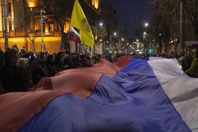 People hold a large Russian flag during a rally in support of Russia in Belgrade, Serbia, Friday, March 4, 2022. Serbia rejects calls from the European Union to join sanctions against Russia, citing national interests. (Photo by Marko Drobnjakovic/AP Photo)