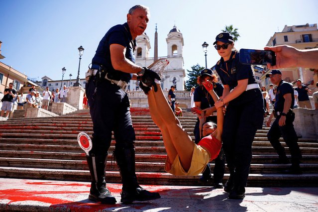 “Bruciamo tutto” (Let's burn everything) activist is removed by police after she poured red paint on the Spanish Steps to protest against femicides in Rome, Italy, on June 26, 2024. (Photo by Guglielmo Mangiapane/Reuters)