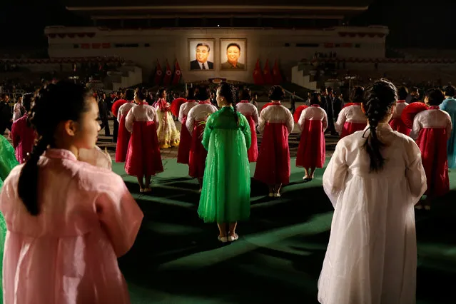 Portraits of North Korea founder Kim Il Sung and late leader Kim Jong Il glow as people take part in a mass dance event marking the 105th birth anniversary of Kim Il Sung in Pyongyang, North Korea April 15, 2017. (Photo by Damir Sagolj/Reuters)