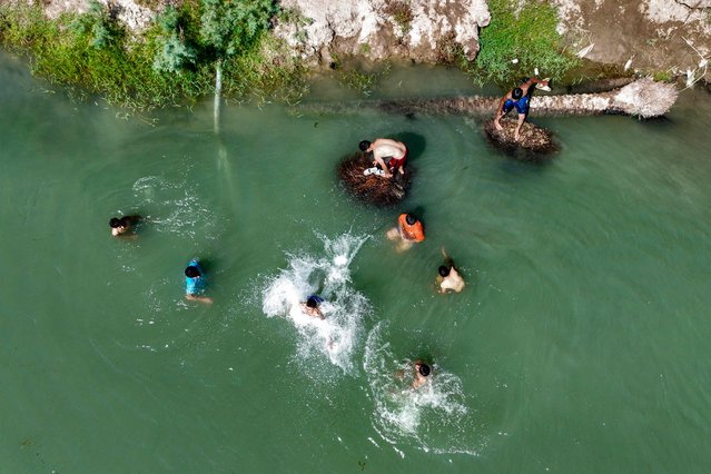 This aerial view shows youths swimming to cool off in the waters of Iraq's Euphrates river during a heatwave, in the district of al-Hindiyah east of Karbala on June 7, 2024. (Photo by Karar Jabbar/AFP Photo)