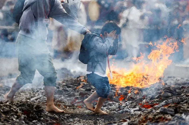 A boy and a man walk next to flames as they walk over coal with barefoot at the fire-walking festival, called Hiwatari Matsuri in Japanese, at Mt.Takao in Tokyo, Japan, March 13, 2022. About 1,500 Japanese worshipers walk barefoot with Buddhist monks over coals at the annual festival praying for the safety of themselves, to overcome the coronavirus disease (COVID-19) pandemic and for peace in the world, Takao-san Yakuo-in Buddhist temple said. (Photo by Kim Kyung-Hoon/Reuters)