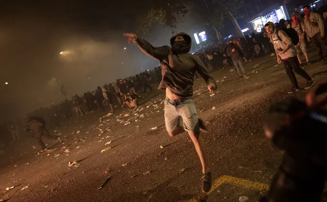 Demonstrators throw stones at police during clashes in Barcelona, Spain, Friday, October 18, 2019.The Catalan regional capital is bracing for a fifth day of protests over the conviction of a dozen Catalan independence leaders. Five marches of tens of thousands from inland towns are converging in Barcelona's center for a mass protest. (Photo by Emilio Morenatti/AP Photo)