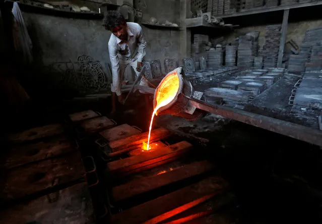 A worker pours molten iron from a ladle to make lamp posts inside an iron casting factory in Ahmedabad, India March 1, 2017. (Photo by Amit Dave/Reuters)