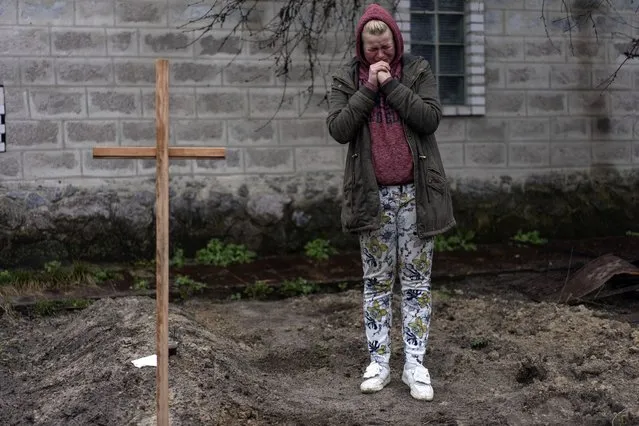 Mariya Ol'hovs'ka mourns the death of her 72-year-old father Valerii Ol'hovs'kyi, killed by a Russian missile days earlier near his home, on the outskirts of Kyiv, Ukraine, Friday, April 1, 2022. Maria and her family buried her father in the garden of their home as they could not bury him in the village cemetery due to fighting between the Ukrainian and Russian armies. (Photo by Rodrigo Abd/AP Photo)
