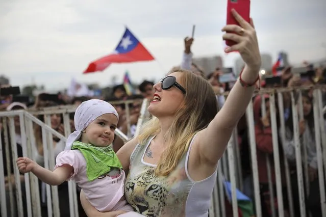Veronica Gosgling sings with her two-year-old daughter Aurora and takes a selfie during an anti-government music concert in O'Higgins Park in Santiago, Chile, Sunday, October 27, 2019. Days of demonstrations have been calling for better pay, pensions, schools, housing and medical care, among many other demands. (Photo by Rodrigo Abd/AP Photo)