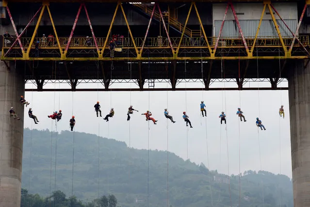People slide down a rope from a bridge during a rescue training in Chongqing, China, May 22, 2016. (Photo by Reuters/China Daily)