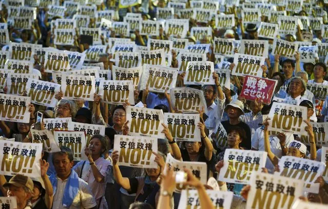 People hold placards denouncing Japan's Prime Minister Shinzo Abe's security-related legislation during an anti-government rally in Tokyo July 24, 2015. (Photo by Thomas Peter/Reuters)