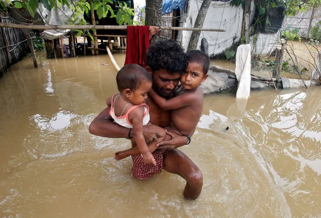 A man carries his children out of their flooded hut to move to a safer place after heavy rains, on World Environment Day, on the outskirts of Agartala, India, June 5, 2017. (Photo by Jayanta Dey/Reuters)