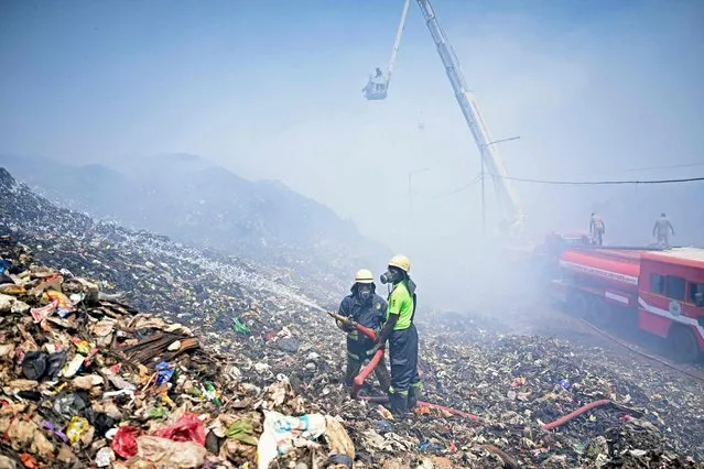 Firefighters try to extinguish burning garbage after a fire broke out at the Perungudi landfill in Chennai on April 29, 2022. (Photo by Arun Sankar/AFP Photo)