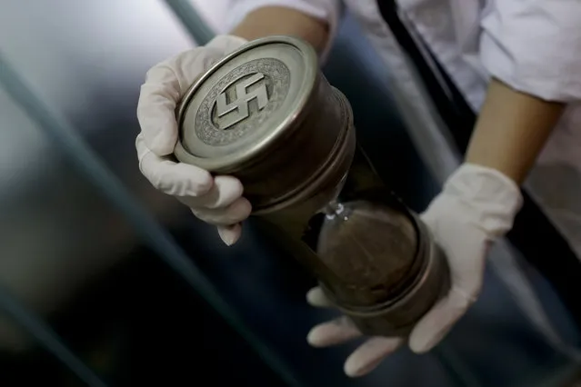 A member of the federal police holds an hourglass with Nazi markings at the Interpol headquarters in Buenos Aires, Argentina, Friday, June 16, 2017. (Photo by Natacha Pisarenko/AP Photo)