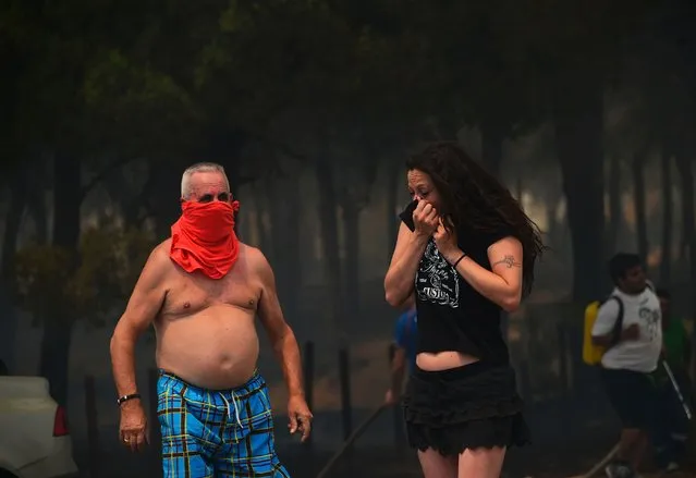 Locals cover their mouth and nose with fabrics or clothes as smoke billows during a wildfire in Mazagon, next to the Donana National Park on July 25, 2017.
More than 1,500 people were evacuated as a precaution on June 25, 2017 after a fire broke out at a nature reserve in southern Spain famed for its biodiversity. The fire started overnight and had by morning encroached on the Donana National Park at Moguer in the southern region of Andalusia, Jose Fiscal, deputy head of the regional environment protection authority, told Spanish television. (Photo by Cristina Quicler/AFP Photo)