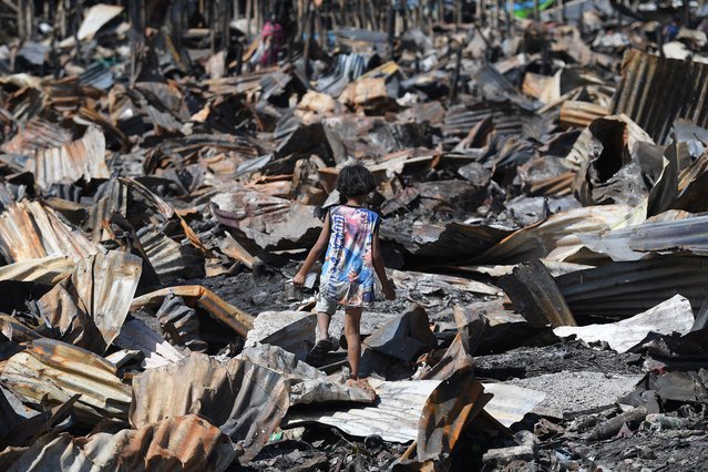 A child looks for salvageable items among charred remains of houses following a fire the previous day in Bacoor town, Cavite province, west of Manila on September 11, 2024. Hundreds of residents were affected by the blaze, with no deaths reported. (Photo by Ted Aljibe/AFP Photo)