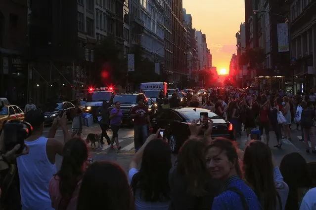 People take pictures at sunset, during the bi-annual occurrence “Manhattanhenge” in New York July 11, 2014. Manhattanhenge, coined by astrophysicist Neil deGrasse Tyson, occurs when the setting sun aligns itself with the east-west grid of streets in Manhattan, allowing the sun to shine down all streets at the same time. (Photo by Eduardo Munoz/Reuters)