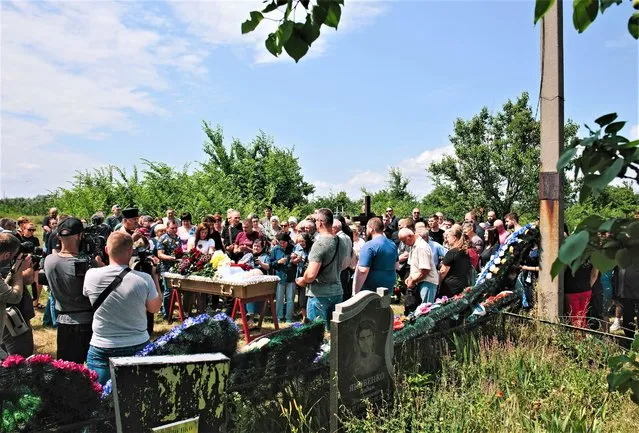 Relatives and friends attend a funeral ceremony for Andriy Krasyuk who was killed in the Russian rocket uring attack on the Amstor shopping mall in Kremenchuk, Ukraine, 30 June 2022. At least 18 people died following Russian airstrikes on the crowded shopping mall, the State Emergency Service (SES) of Ukraine said. The Amstor shopping center one-story building was hit by Russian rockets on 27 June afternoon. Russian troops on 24 February entered Ukrainian territory, starting a conflict that has provoked destruction and a humanitarian crisis. (Photo by Pavlo Pakhomenko/EPA/EFE/Rex Features/Shutterstock)