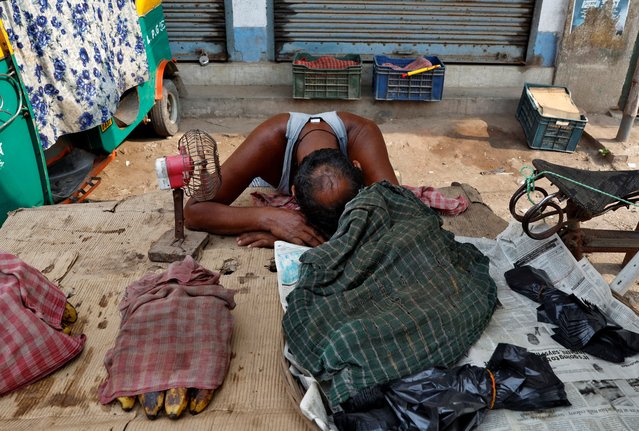 A vendor uses a fan to cool himself as he waits for customers on a hot summer day on the outskirts of Kolkata, India, on May 2, 2024. (Photo by Sahiba Chawdhary/Reuters)