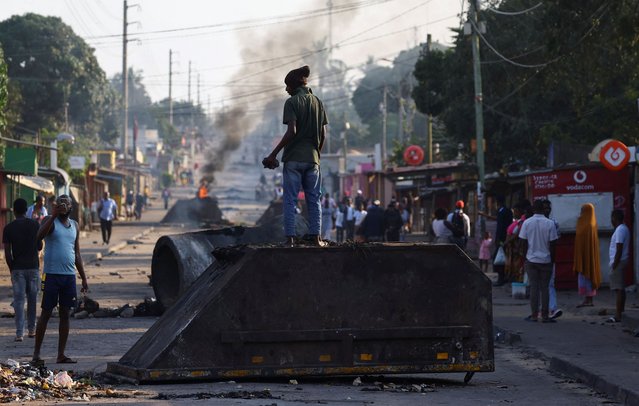 A man stands on an overturned bin used by protesters as a barricade, after the ruling Frelimo party was declared the winner of this month's disputed election, in Maputo, Mozambique, on October 25, 2024. (Photo by Siphiwe Sibeko/Reuters)