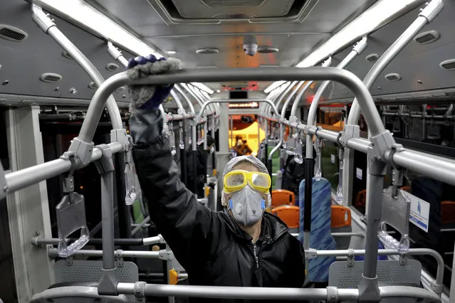 A worker disinfects a public bus against coronavirus in Tehran, Iran, in early morning of Wednesday, February 26, 2020. Iran's government said Tuesday that more than a dozen people had died nationwide from the new coronavirus, rejecting claims of a much higher death toll of 50 by a lawmaker from the city of Qom that has been at the epicenter of the virus in the country. (Photo by Ebrahim Noroozi/AP Photo)