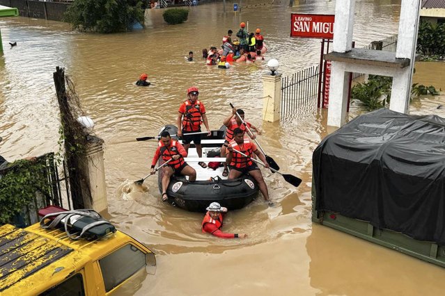 In this photo provided by the Philippine Coast Guard, rescuers navigate a flooded area as they look for residents trapped in their homes after heavy rains from Tropical Storm Trami  inundate their village at Nabua, Camarines Sur province, Philippines Thursday, October 24, 2024. (Photo by Philippine Coast Guard via AP Photo)