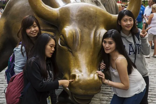 Tourists pose for photographs with a landmark statue of a bull in New York August 24, 2015.  Wall Street opened sharply lower on Monday with the Dow Jones industrial average losing more than a 1,000 points following a more-than 8 percent drop in Chinese shares and a selloff in oil and other commodities. (Photo by Lucas Jackson/Reuters)