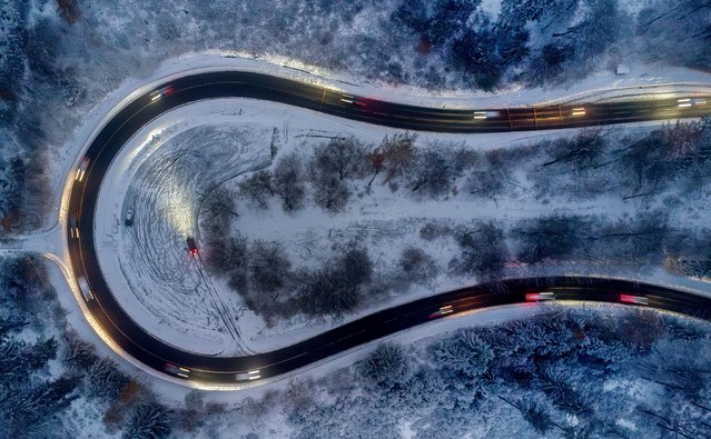 Cars drive through curve in a forest of the Taunus region near Frankfurt, Germany, after snow falls during the night on Thursday, November 21, 2024. (Photo by Michael Probst/AP Photo)