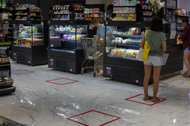 Customers stand in an area marked to prompt social distancing leading to cashers at a supermarket in Bangkok, Thailand, Tuesday, March 24, 2020. Most popular shopping malls remained shut in Bangkok, except supermarkets and pharmacies to combat the spread of new coronavirus. (Photo by Gemunu Amarasinghe/AP Photo)