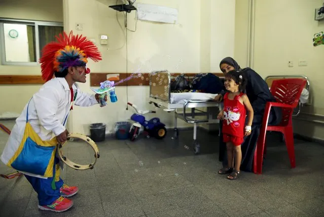A Palestinian social activist working for the International South South Cooperation (Cooperazione Internazionale Sud Sud, or CISS) entertain a child who is a cancer patient, inside a hospital in Gaza City August 31, 2015. (Photo by Mohammed Salem/Reuters)