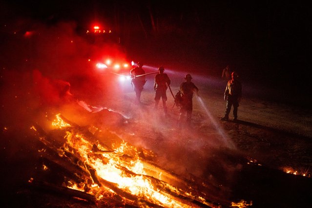 Firefighters douse flames while battling a wildfire called the Highland Fire in Aguanga, Calif., Monday, October 30, 2023. A wildfire fueled by gusty Santa Ana winds ripped through rural land southeast of Los Angeles on Monday, forcing thousands of people from their homes, fire authorities said. (Photo by Ethan Swope/AP Photo)