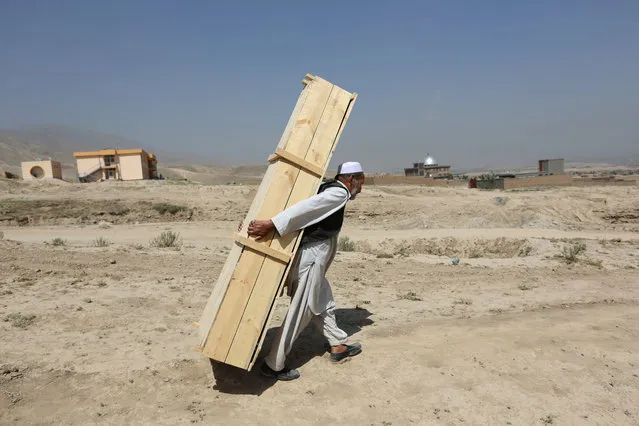 An Afghan man carries an empty casket for a funeral ceremony, in Kabul, Afghanistan, Monday, July 25, 2016. Afghanistan held a national day of mourning on Sunday, a day after a suicide bomber killed at least 80 people who were taking part in a peaceful demonstration in Kabul. The attack was claimed by the Islamic State group. (Photo by Rahmat Gul/AP Photos)