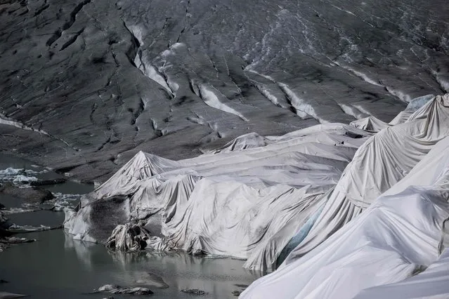 This photograph taken near Gletsch, in the Swiss Alps, on July 8, 2022 shows insulating foam covering a part of the Rhone Glacier to prevent it from melting next to its glacial lake, formed by the melting of the glacier due to global warming. The Rhone Glacier has been selected among ten glaciers across the world to be monitored by high resolution time-lapse cameras as part of the Planet Watch projet launched by French digital image solution startup Enlaps, helping to document and measure the impact of global warming. (Photo by Fabrice Coffrini/AFP Photo)