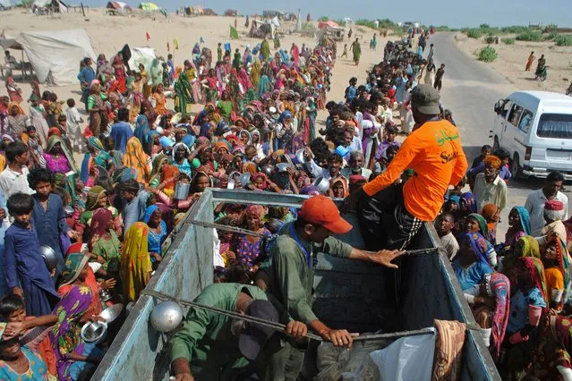 Internally displaced people gather to receive free food near their makeshift camp in the flood-hit Chachro of Sindh province on September 19, 2022. (Photo by AFP Photo/Stringer)