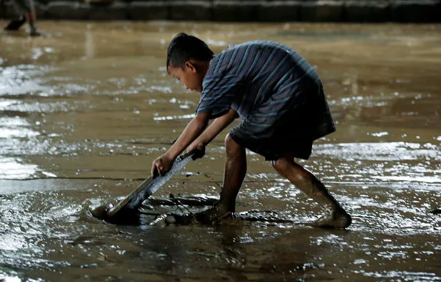 A resident removes mud brought by flooding from monsoon rains at an evacuation centre in San Mateo, Rizal, Philippines, August 14, 2016. (Photo by Erik De Castro/Reuters)