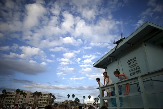 Children watch the Nashuva Spiritual Community Jewish New Year celebration from a lifeguard station on Venice Beach in Los Angeles, California, United States September 14, 2015. (Photo by Lucy Nicholson/Reuters)