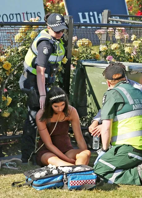 A racegoer is assisted by ambulance workers following 2017 Stakes Day at Flemington Racecourse on November 11, 2017 in Melbourne, Australia. (Photo by Getty Images/Stringer)