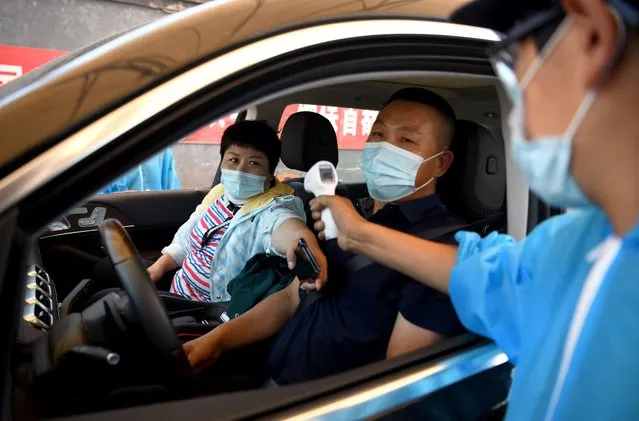 A security personnel wearing a protective suit checks the temperature of people entering the Xinfadi market in Beijing on June 14, 2020. The domestic outbreak in China had been brought largely under control through strict lockdowns that were imposed early this year – but a new cluster has been linked to Xinfadi market in south Beijing. (Photo by Noel Celis/AFP Photo)