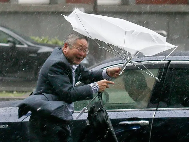 A businessman is struggling with his umbrella broken by wind, against heavy rain in Tokyo, Japan, 06 October 2014. Typhoon Phanfone is hitting through southwestern, western and central Japan with heavy rain and strong winds after lashing western and southern Japan, leaving two dead and three missing. (Photo by Kimimasa Mayama/EPA)