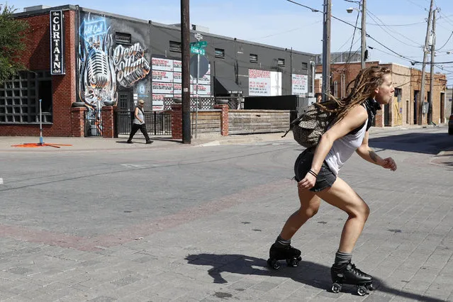 A woman skates through an intersection in the Deep Ellum entertainment district in Dallas, Friday, June 26, 2020. Deep Ellum is destination well known for its restaurants, cafes, tattoo shops and live music venues. Texas Gov. Greg Abbott announced Friday that he is shutting bars back down and scaling back restaurant capacity to 50%, in response to the increasing number of COVID-19 cases in the state. (Photo by Tony Gutierrez/AP Photo)