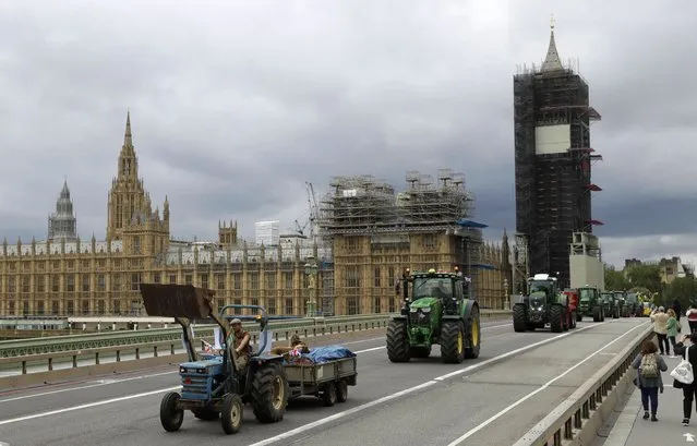 Farmers from the group Save British Farming drive tractors across Westminster Bridge, backdropped by the Houses of Parliament and the scaffolded Big Ben tower in London, in a protest against cheaply produced lower standard food being imported from the U.S. after Brexit that will undercut them, Wednesday, July 8, 2020. (Photo by Matt Dunham/AP Photo)
