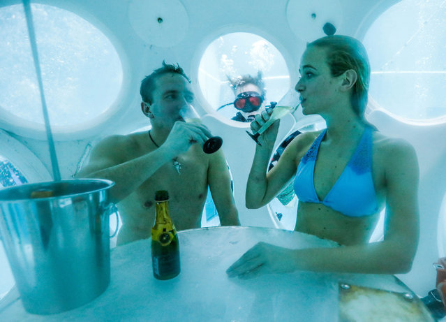 Belgians Florence Lutje Spelberg and Nicolas Mouchart drink champagne while sitting inside “The Pearl”, a spheric dining room placed 5 metres underwater in the NEMO33 diving center, one of the world's deepest pools (33 metre/36 yards) built to train professional divers, before enjoying a meal inside, in Brussels, Belgium January 30, 2017. (Photo by Yves Herman/Reuters)