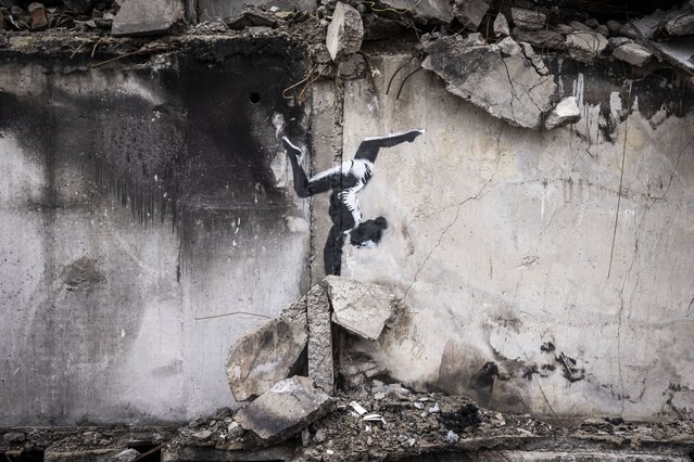 Graffiti of a woman in a leotard doing a handstand is seen on the wall of a destroyed building in Borodyanka on November 11, 2022 in Kyiv Region, Ukraine. Similar art work nearby sparked online speculation over whether the graffiti artist Banksy has been working in Ukraine. Borodyanka was hit particularly hard by Russian airstrikes in the first few weeks of the conflict. Electricity and heating outages across Ukraine caused by missile and drone strikes to energy infrastructure have added urgency to preparations for winter. (Photo by Ed Ram/Getty Images)