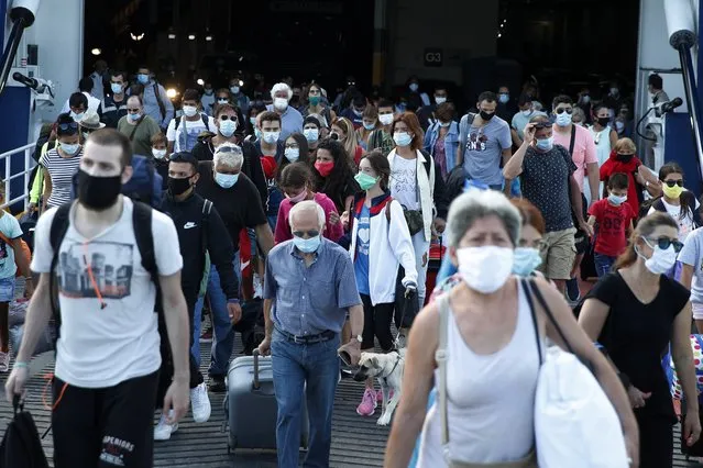 Travellers wearing face masks against the spread of the new coronavirus, disembark from a ferry at the port of Piraeus, near Athens, Thursday, August 20, 2020. Greece initially managed to keep the number of coronavirus cases and deaths low, imposing an early lockdown at the start of the pandemic. But most restrictions were lifted at the start of the summer, and the tourism-reliant country has welcomed in foreign visitors for the summer vacation period. (Photo by Thanassis Stavrakis/AP Photo)