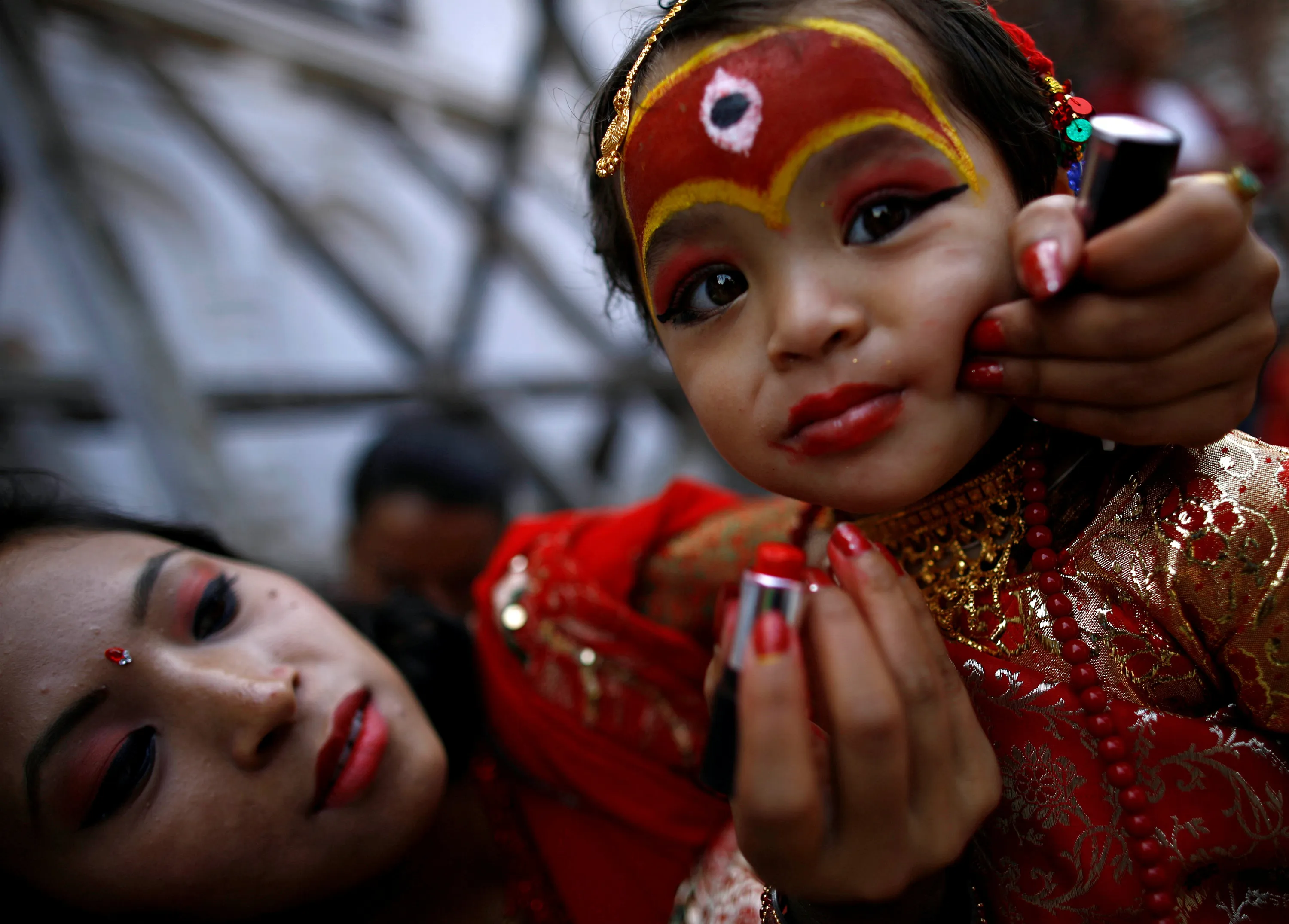 A woman applies makeup to the face of a young girl dressed as the Living Go...