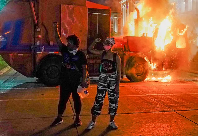 Two protestors stand with raised fists as a garbage truck burns behind them during a second night of unrest in the wake of the shooting of Jacob Blake by police officers, in Kenosha, Wisconsin, USA, 24 August 2020. According to media reports Jacob Blake, a black man, was shot by a Kenosha police officer or officers responding to a domestic distubance call on 23 August, setting off protests and unrest. Blake was taken by air ambulance to a Milwaukee, Wisconsin hospital and protests started after a video of the incident was posted on social media. (Photo by Tannen Maury/EPA/EFE)