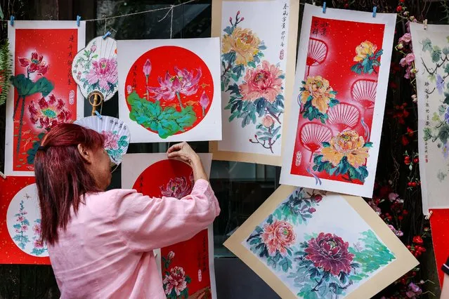 A woman hangs chinese art pieces on display at Kwai Chai Hong, a heritage revival back alley in Chinatown on January 15, 2023 in Kuala Lumpur, Malaysia. (Photo by Annice Lyn/Getty Images)