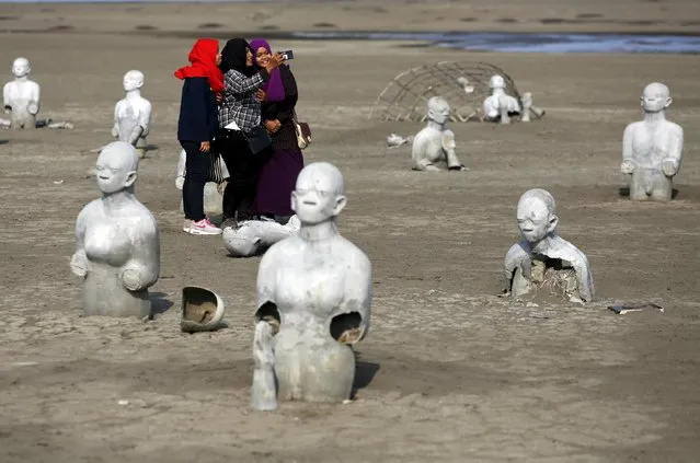 Women take pictures between stone sculptures of half-buried people at the Lapindo mud field in Sidoarjo, October 11, 2015. Disaster tourism has become more common in Indonesia, where visitors are drawn to sites of earthquakes, floods and volcanic eruptions to witness the aftermath of catastrophes or simply do some soul-searching. (Photo by Reuters/Beawiharta)