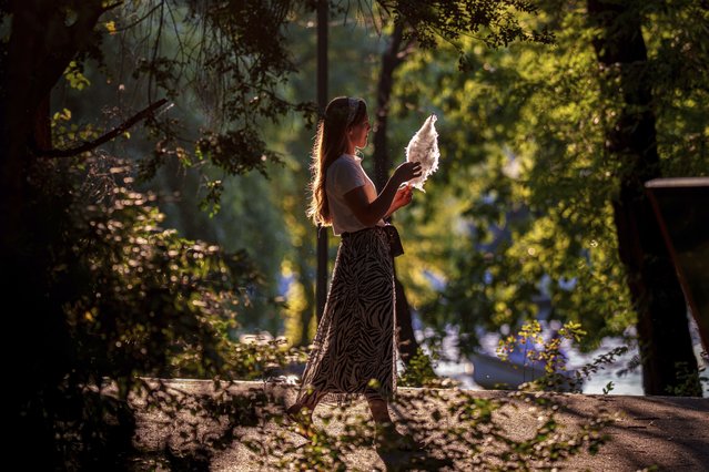 A woman eats cotton candy while walking in the Cismigiu park in Bucharest, Romania, Saturday, August 2, 2025. (Photo by Andreea Alexandru/AP Photo)