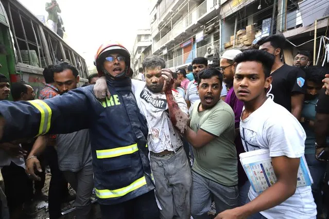Fire officials and locals carry an injured person to hospital after an explosion, in Dhaka, Bangladesh, Tuesday, March 7, 2023. An explosion in a seven-story commercial building in Bangladesh's capital has killed at least 14 people and injured dozens. Officials say the explosion occurred in a busy commercial area of Dhaka. (Photo by AP Photo/Stringer)