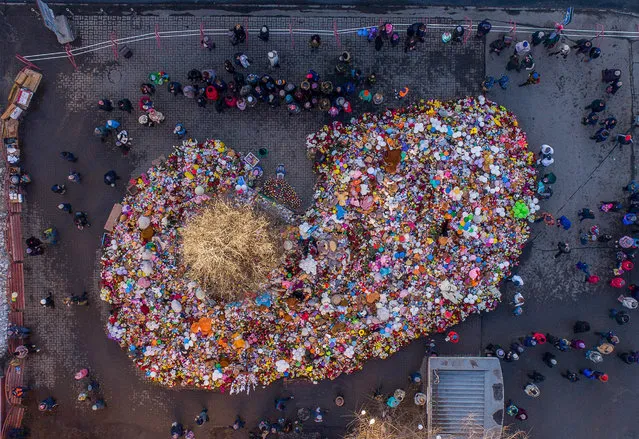 An aerial view taken with a drone on March 29, 2018 shows people visiting a makeshift memorial in tribute to the victims of a shopping mall fire in the industrial city of Kemerovo in western Siberia. (Photo by Dmitry Serebryakov/AFP Photo)