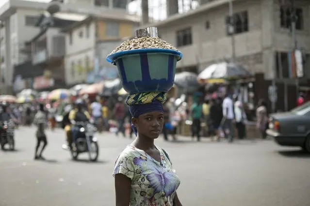 A Sierra Leonen woman carries a pot of peanuts on her head in Freetown, Sierra Leone, December 16, 2014. (Photo by Baz Ratner/Reuters)