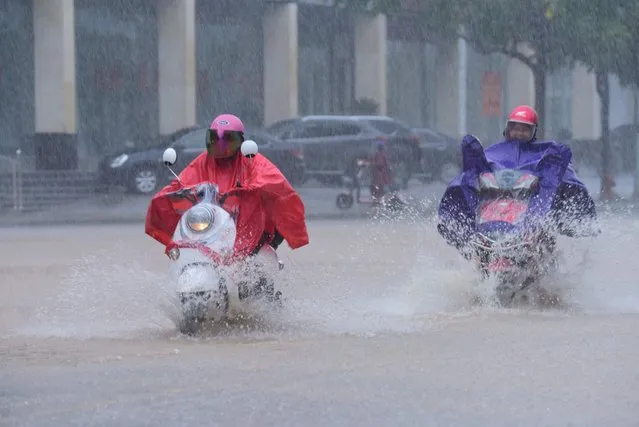 Citizens wearing raincoats ride in the rain brought by typhoon Vamco on November 15, 2020 in Qionghai, Hainan Province of China. (Photo by Meng Zhongde/VCG via Getty Images)